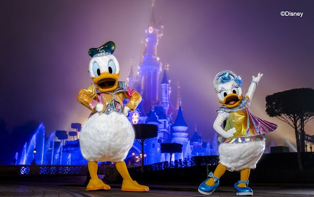 Disney characters in front of Sleeping Beauty Castle at Disneyland Paris.