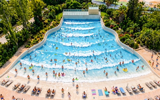 Visitors enjoying the wave pool at Aquasplash Antibes, surrounded by lush greenery.