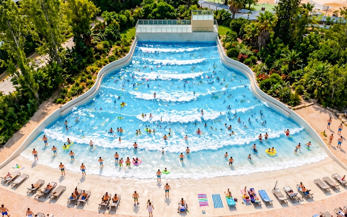 Visitors enjoying the wave pool at Aquasplash Antibes, surrounded by lush greenery.