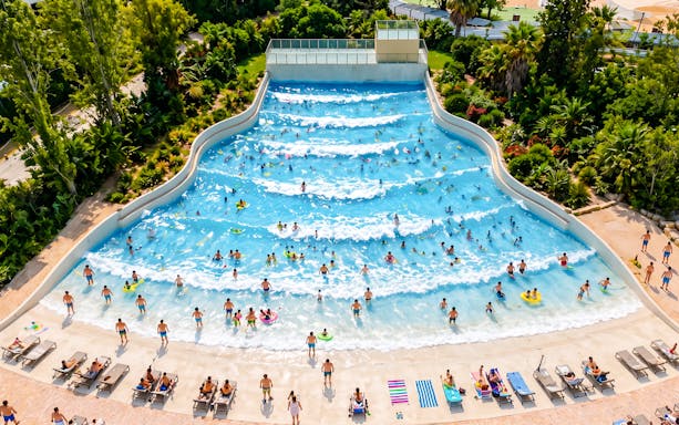 Visitors enjoying the wave pool at Aquasplash Antibes, surrounded by lush greenery.
