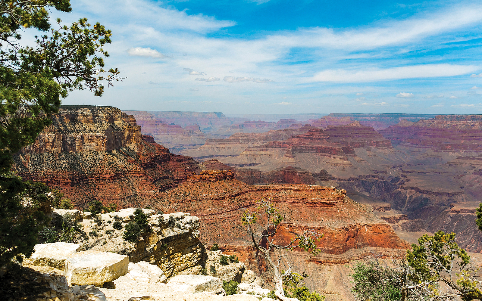 North Grand Canyon view with layered rock formations under a blue sky.