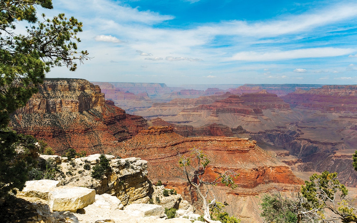 North Grand Canyon view with layered rock formations under a blue sky.