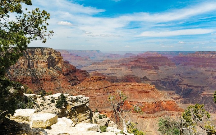 North Grand Canyon view with layered rock formations under a blue sky.