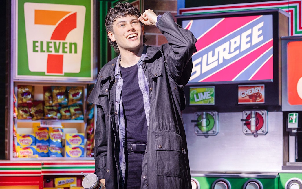 Performer in front of 7-Eleven set during Heathers: The Musical.