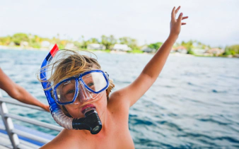 Kid wearing snorkel gear on a boat near Kohala Coast, Big Island.