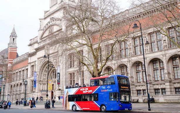 Golden Tours hop-on hop-off bus in front of the Victoria and Albert Museum, London.
