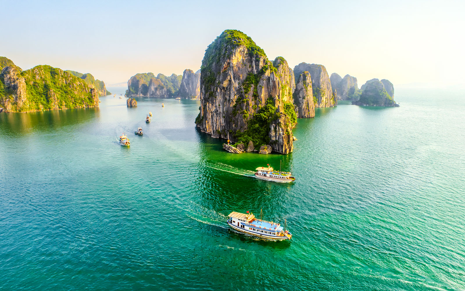 Halong Bay cruise ship sailing past limestone karsts in Vietnam.