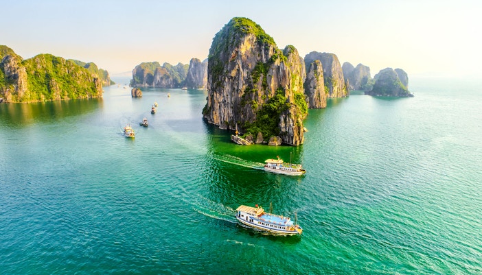 Halong Bay cruise ship sailing past limestone karsts in Vietnam.