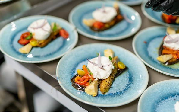 Italian appetizer with burrata and roasted vegetables on a blue plate, Paris dinner cruise.
