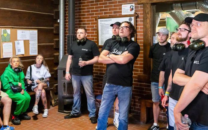 Group of people listening to instructions at an indoor shooting range.