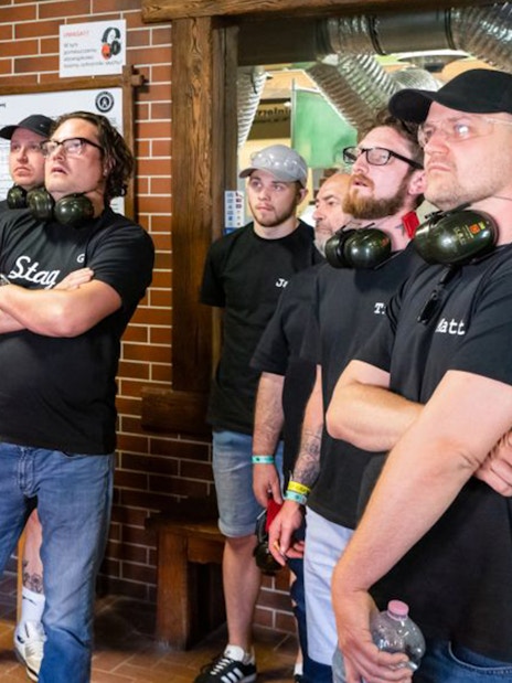 Group of people listening to instructions at an indoor shooting range.