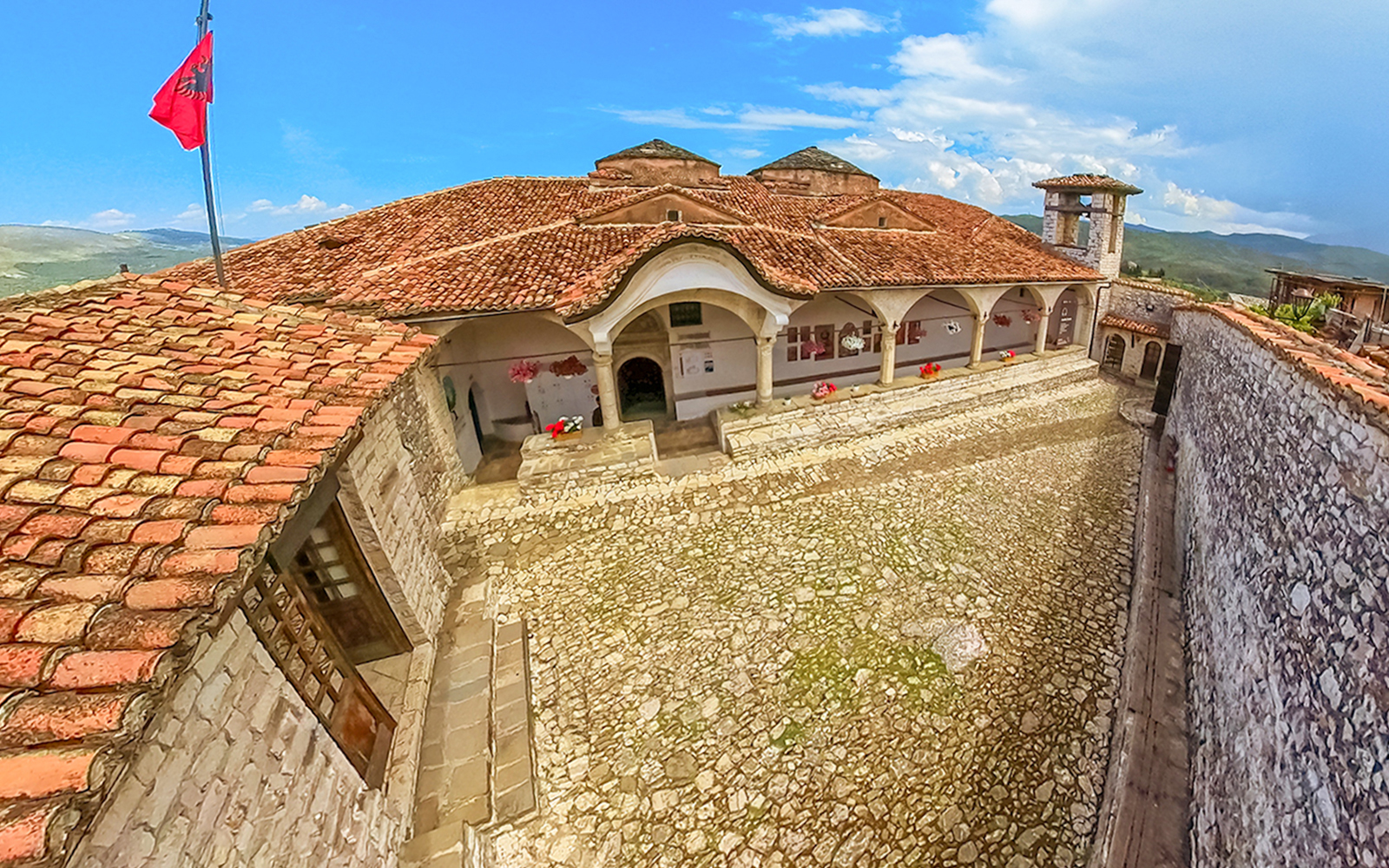 Exterior of Onufri National Iconographic Museum in Berat with stone courtyard and red-tiled roof.