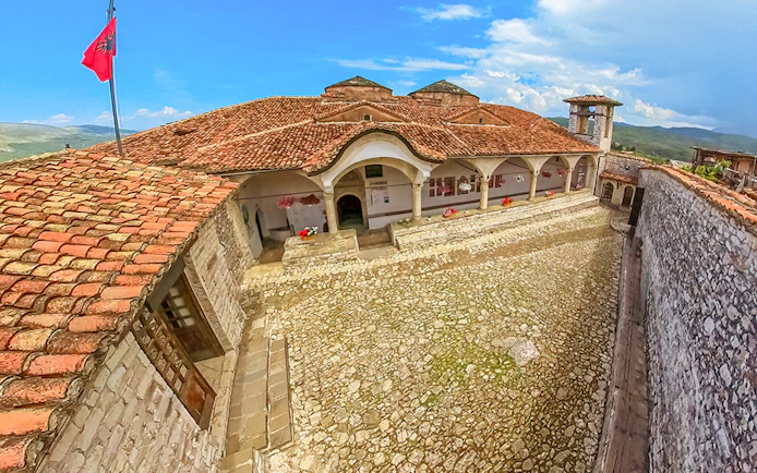 Exterior of Onufri National Iconographic Museum in Berat with stone courtyard and red-tiled roof.