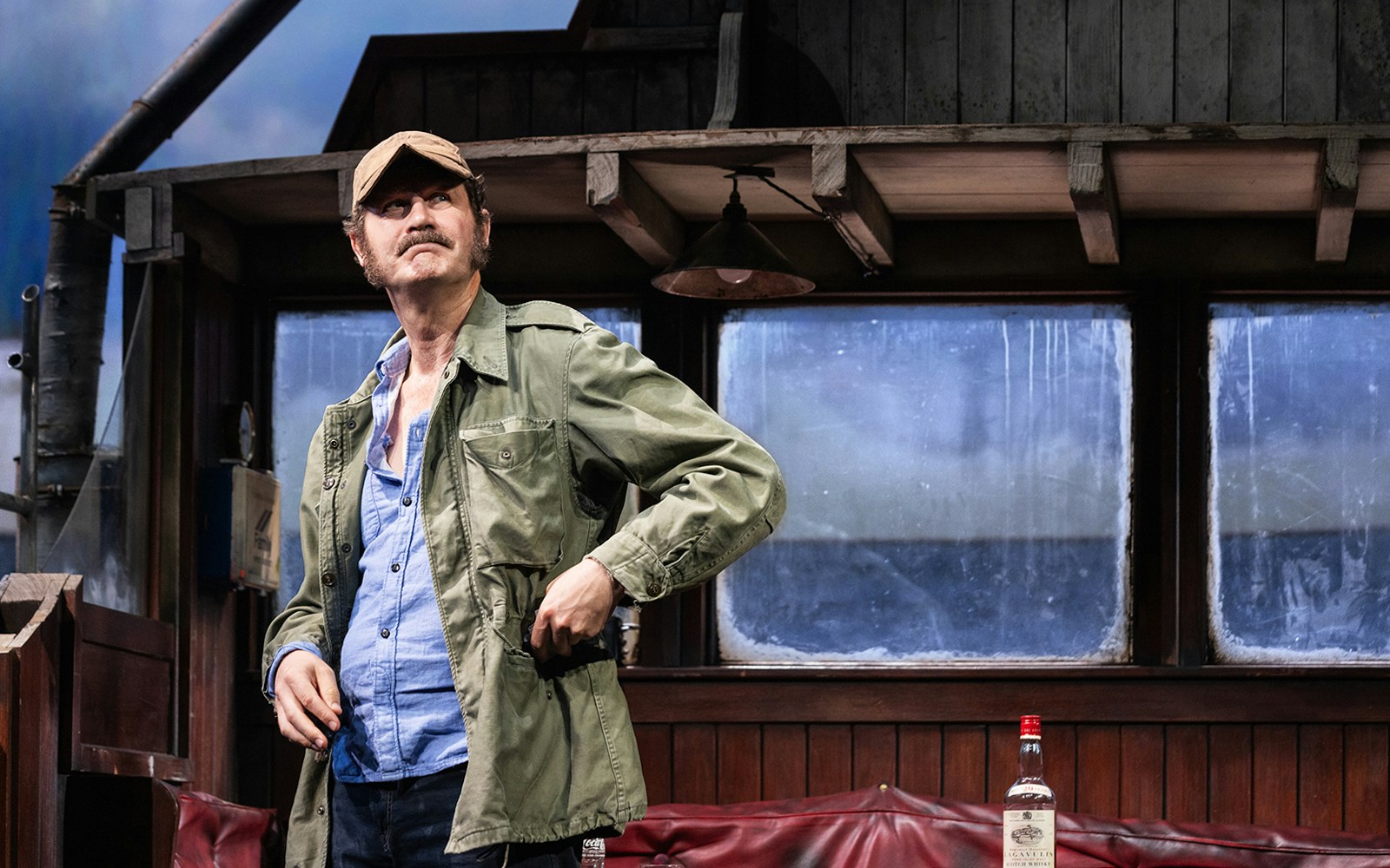 Man in a cap and jacket on a boat set from "The Shark is Broken" play.