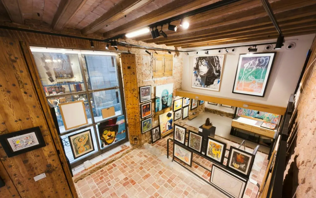 Art gallery interior with various paintings on brick walls, part of Barcelona El Born Walking Tour.