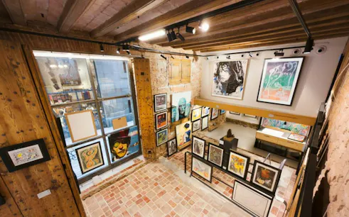 Art gallery interior with various paintings on brick walls, part of Barcelona El Born Walking Tour.