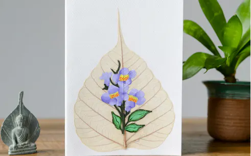 Leaf skeleton art with painted purple flowers at Da Nang workshop.