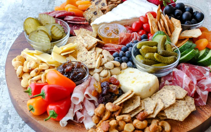 Cheese and charcuterie platter with pickles, nuts, and fruits for Scenic Wine and Cheese Harbour Cruise.