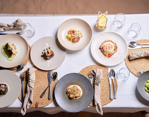 Meal setup at Noble Camp Desert Safari with various gourmet dishes on a table.
