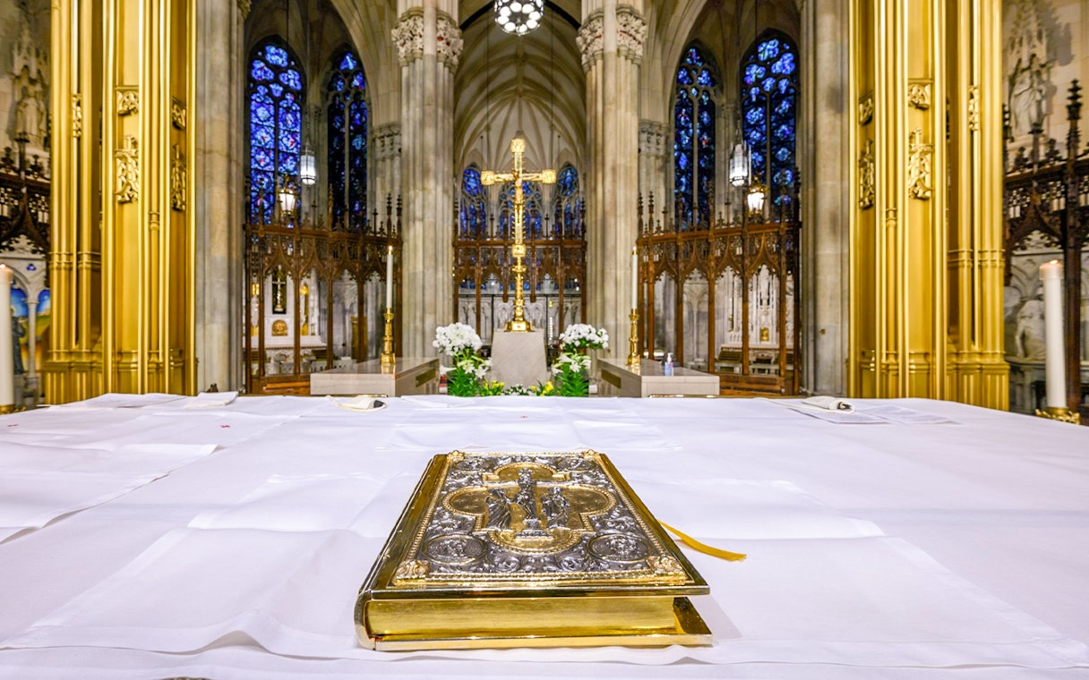 Altar view inside St. Patrick's Cathedral with ornate Bible and golden cross.