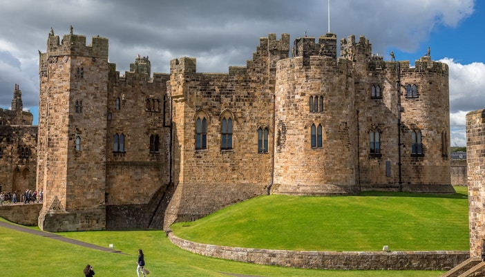 Alnwick Castle exterior with lush green landscape, Edinburgh day tour.