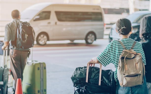 Travelers with luggage waiting for a private airport transfer in Bangkok.