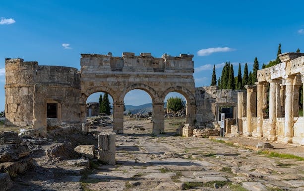 Ancient ruins of Hierapolis with stone arches and columns in Pamukkale, Turkey.