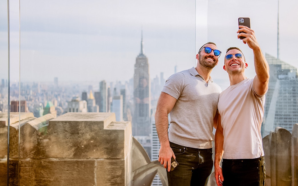 Men taking a selfie at Top of the Rock, with Empire State Building in background, New York.
