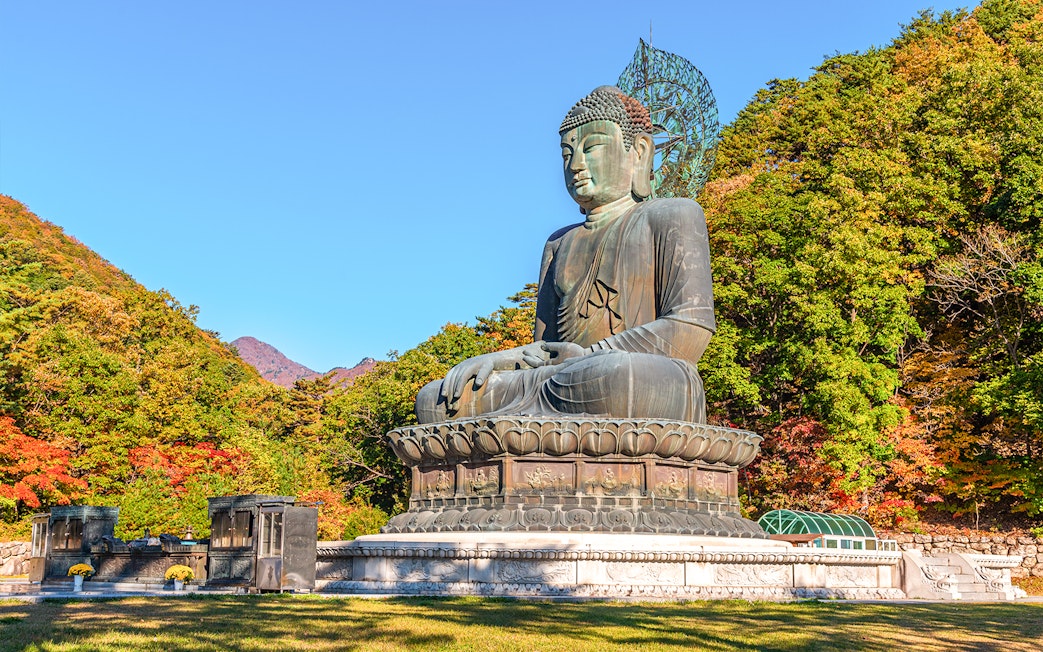 Buddha statue surrounded by autumn trees at Seoraksan National Park, Republic of Korea.