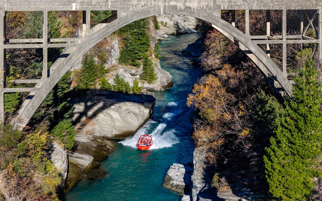 Aerial view of tourists on Shotover Jet navigating a narrow canyon in New Zealand.
