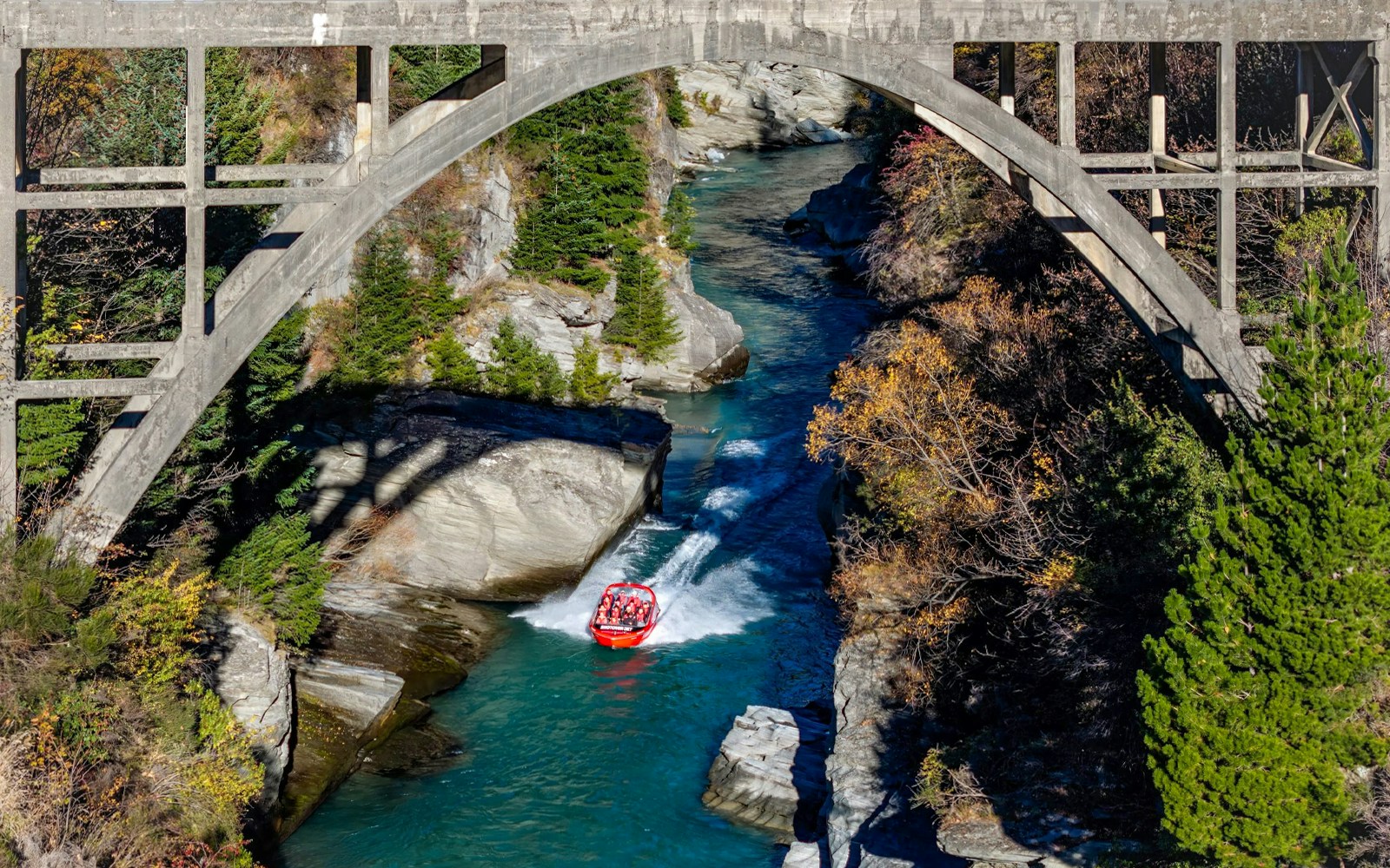 Aerial view of tourists on Shotover Jet navigating a narrow canyon in New Zealand.