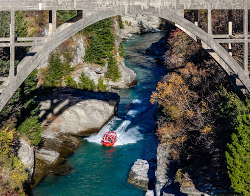 Aerial view of tourists on Shotover Jet navigating a narrow canyon in New Zealand.