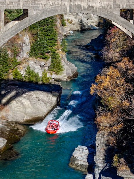 Aerial view of tourists on Shotover Jet navigating a narrow canyon in New Zealand.