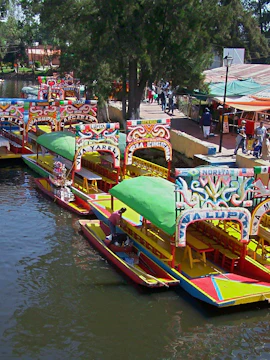 Colorful trajineras on Xochimilco canal with people boarding.