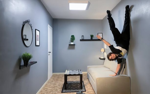 Person appearing to stand sideways on a wall in a Museum of Illusions room.