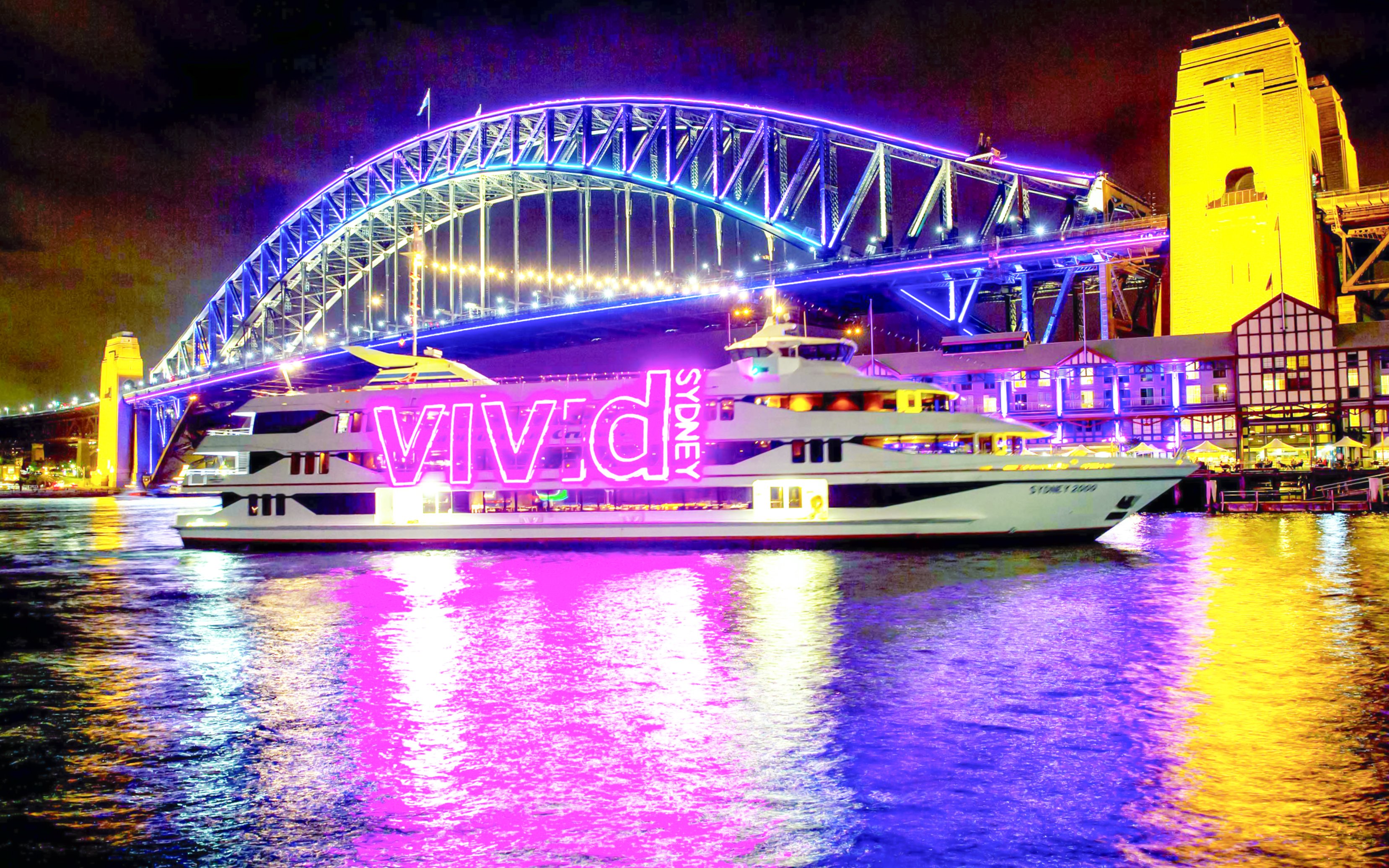 Sydney Harbour Bridge illuminated during Vivid Sydney light show with cruise ship in foreground.