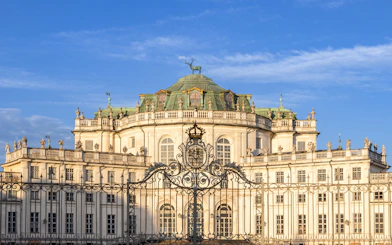 Hunting Lodge of Stupinigi in Turin, Italy, with ornate gate and blue sky.