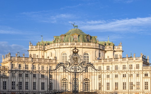 Hunting Lodge of Stupinigi in Turin, Italy, with ornate gate and blue sky.