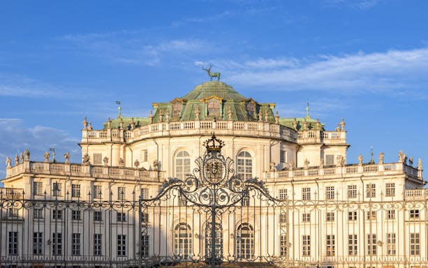 Hunting Lodge of Stupinigi in Turin, Italy, with ornate gate and blue sky.