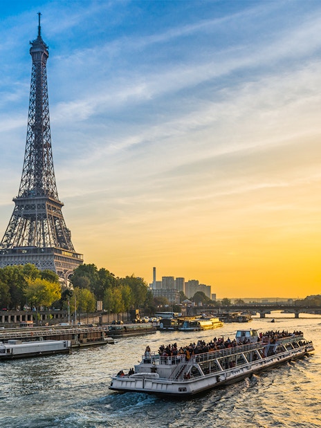 Cruise ship on the Seine River with Eiffel Tower at sunset in Paris.