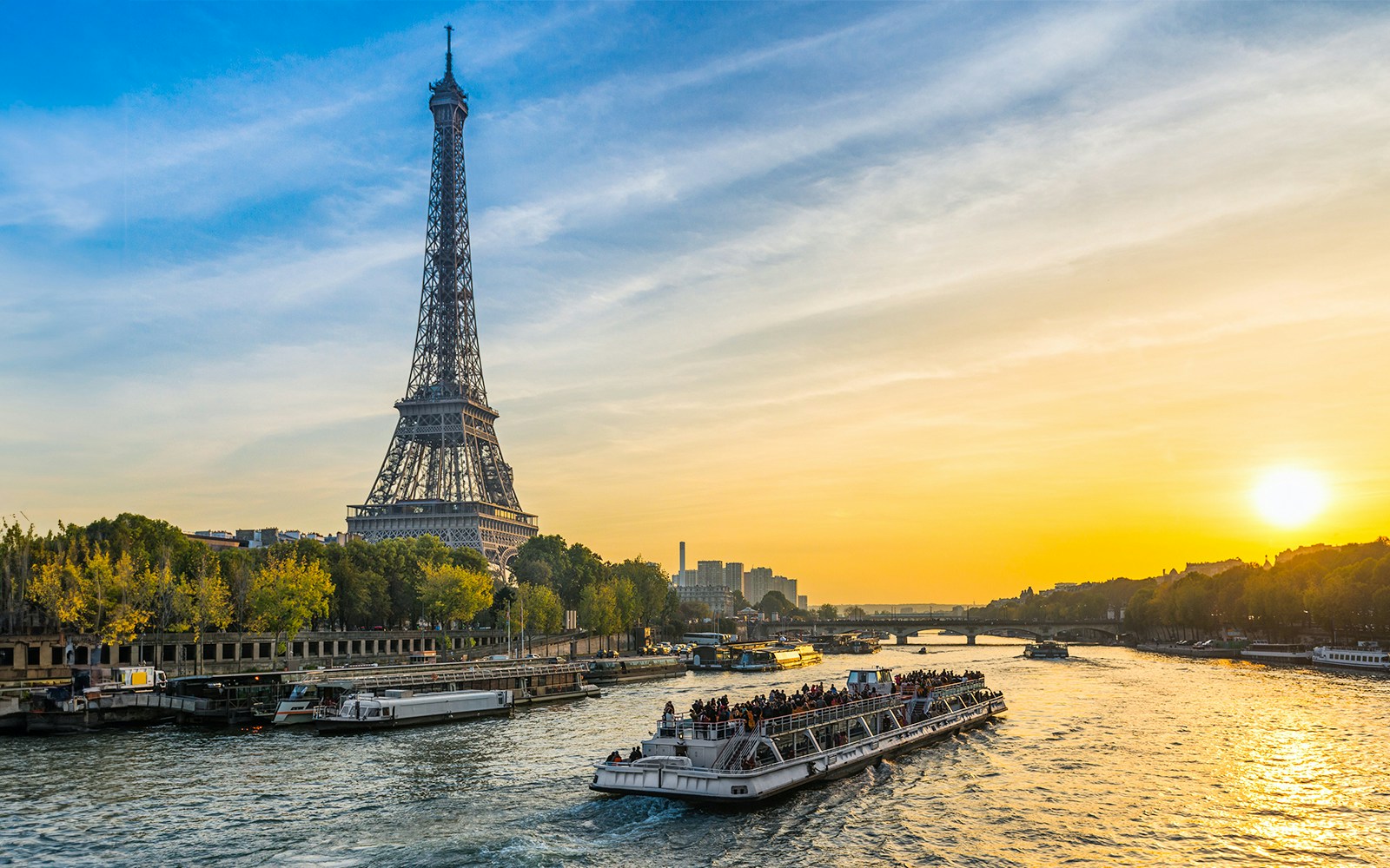 Cruise ship on the Seine River with Eiffel Tower at sunset in Paris.