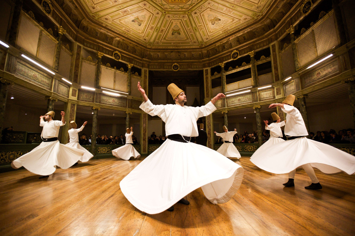 Dervishes performing traditional dance in ornate hall during Dervish Experience.