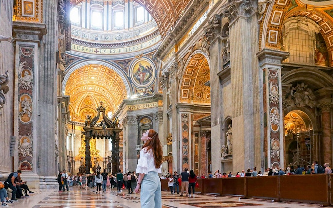 Visitor admiring the ornate interior of St. Peter's Basilica, Vatican City.