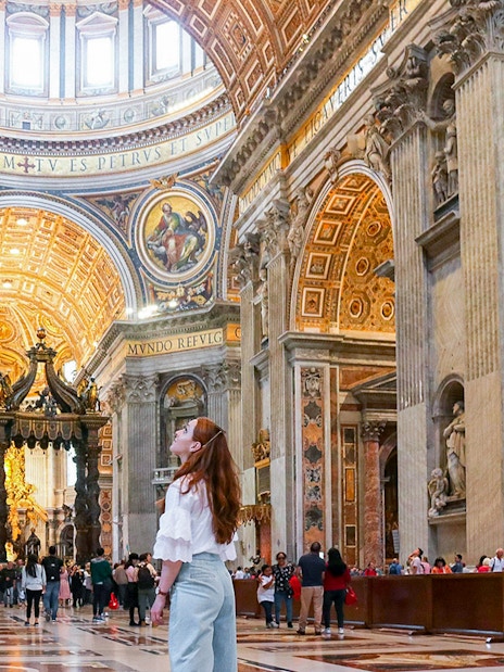Visitor admiring the ornate interior of St. Peter's Basilica, Vatican City.