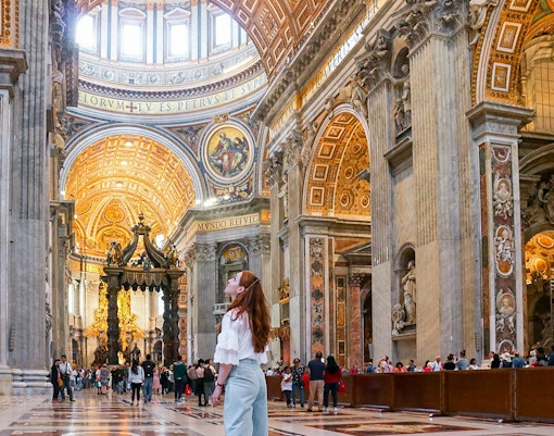 Visitor admiring the ornate interior of St. Peter's Basilica, Vatican City.
