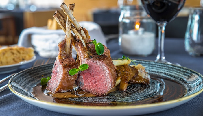 Crispy lamb ribs served on a plate with garnish and sauce.