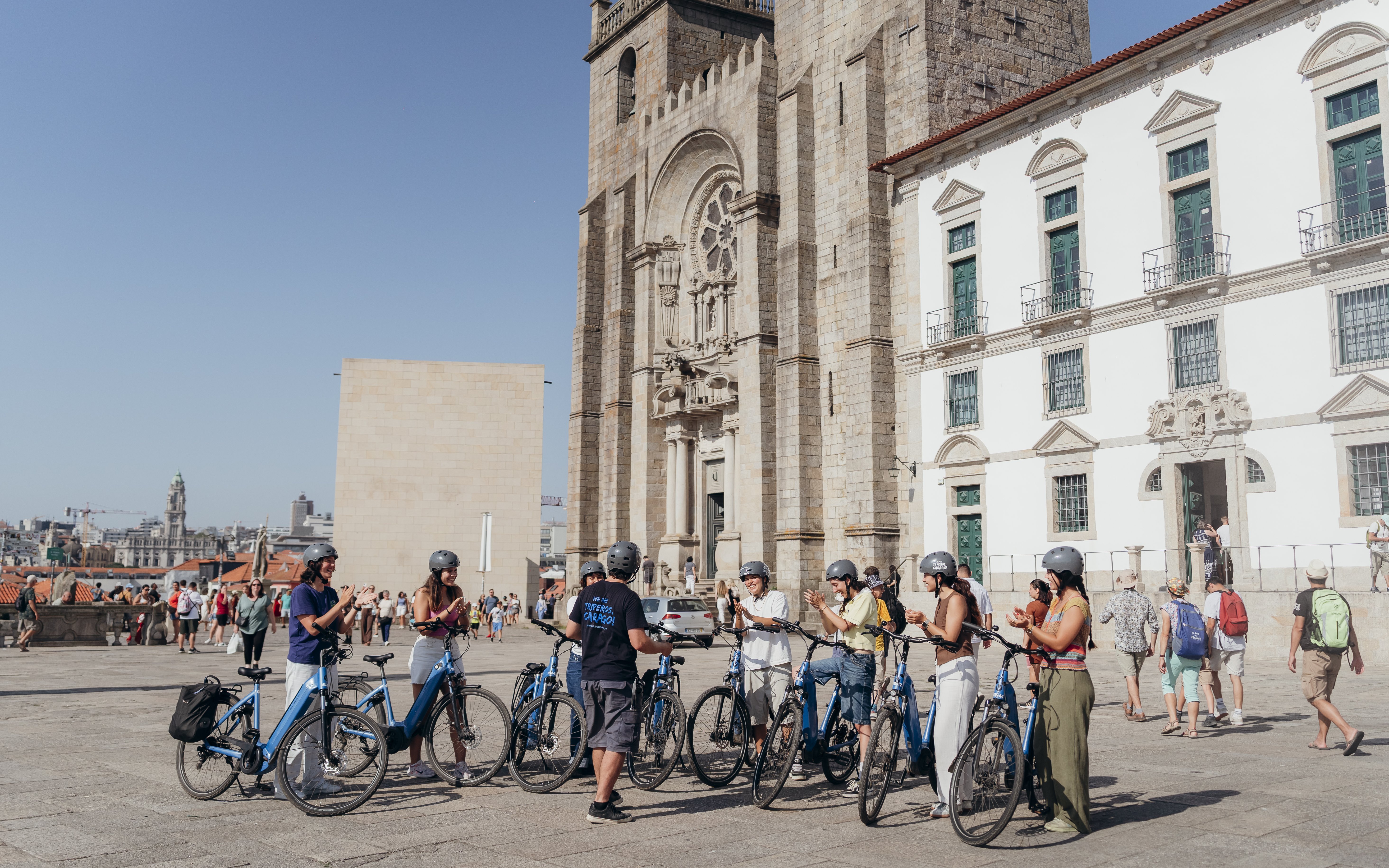 Tourists with guide on electric bikes in front of Porto Cathedral during guided tour.
