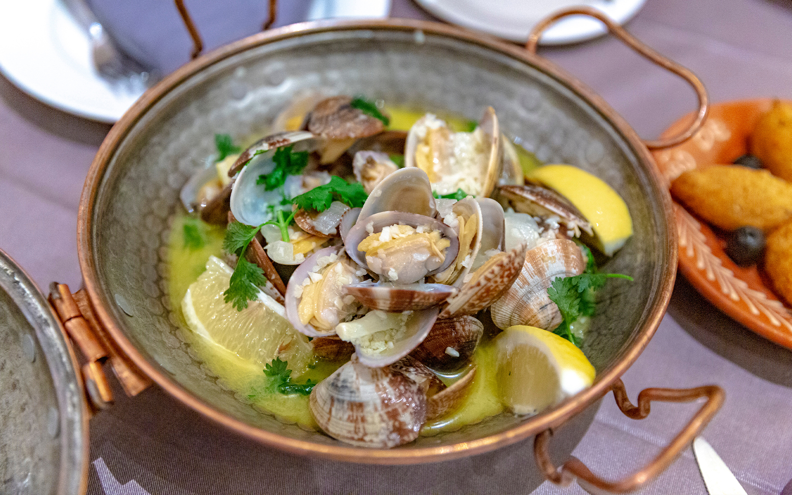 Portuguese clams in white wine sauce with lemon and herbs in a rustic bowl.