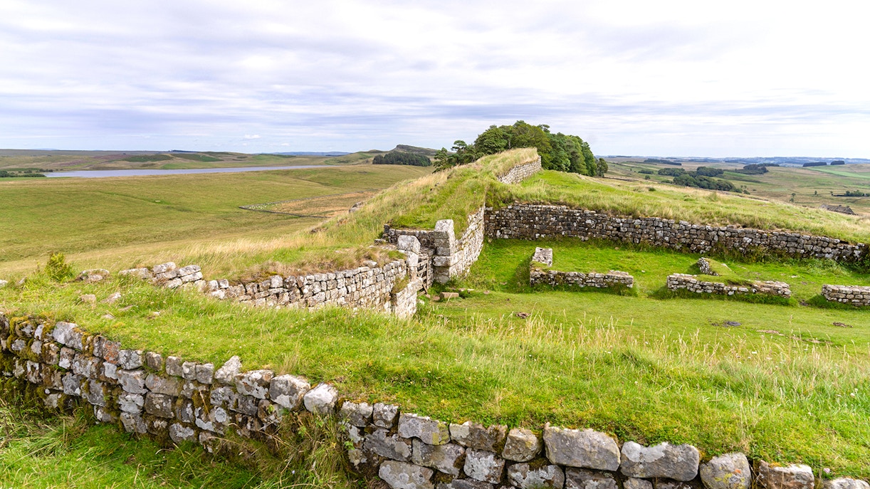 Housesteads Roman Fort ruins with stone walls and green landscape in Northumberland, England.