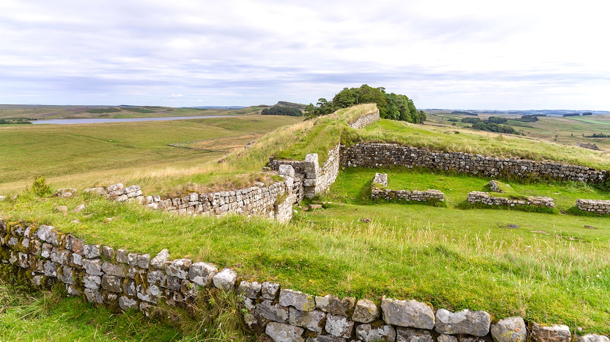 Housesteads Roman Fort ruins with stone walls and green landscape in Northumberland, England.